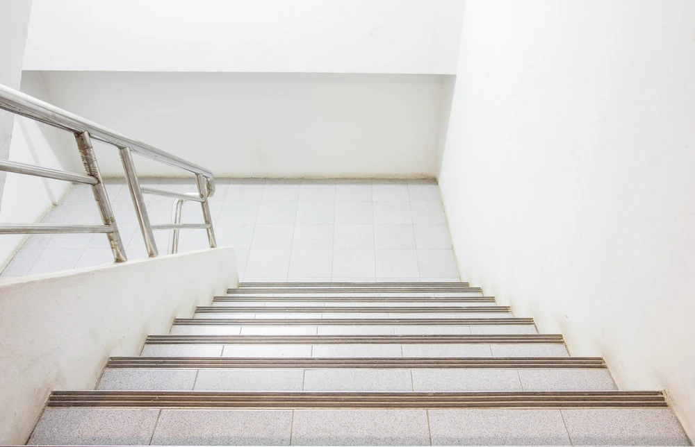 Escalier intérieur moderne en béton avec marches en carrelage beige et nez de marche métalliques