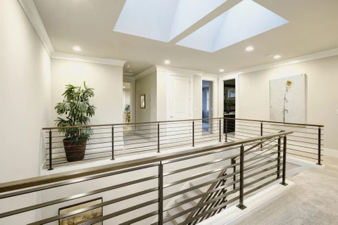 Intérieur moderne d'un étage supérieur avec mezzanine ouverte et garde-corps métalliques à barreaudage horizontal