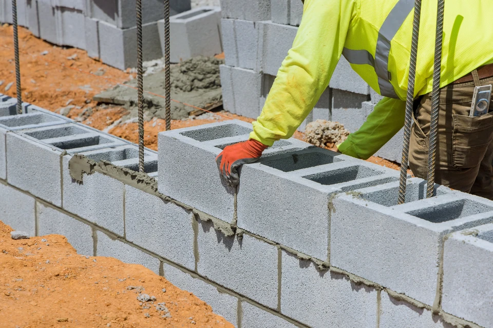 Un maçon est en train de monter un mur de blocs de béton aéré en utilisant des techniques de maçonnerie sur le chantier