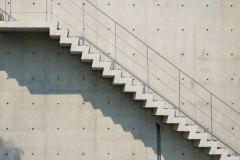 Escalier extérieur en béton brut avec garde-corps métallique et main courante tubulaire