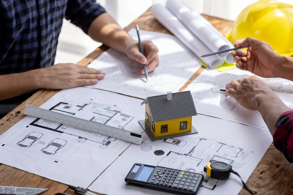 Réunion professionnelle sur un chantier de construction entre l'architecte et les artisans qui portent un masque de protection contre le vid-19