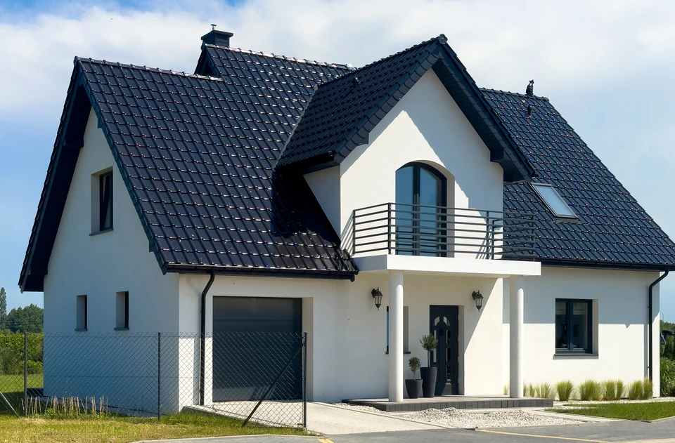 Façade en pierre calcaire d'une maison traditionnelle française avec volets bleus en bois, toiture en tuiles plates, lucarnes à fronton triangulaire, fenêtres à petits carreaux et balconnet en fer forgé