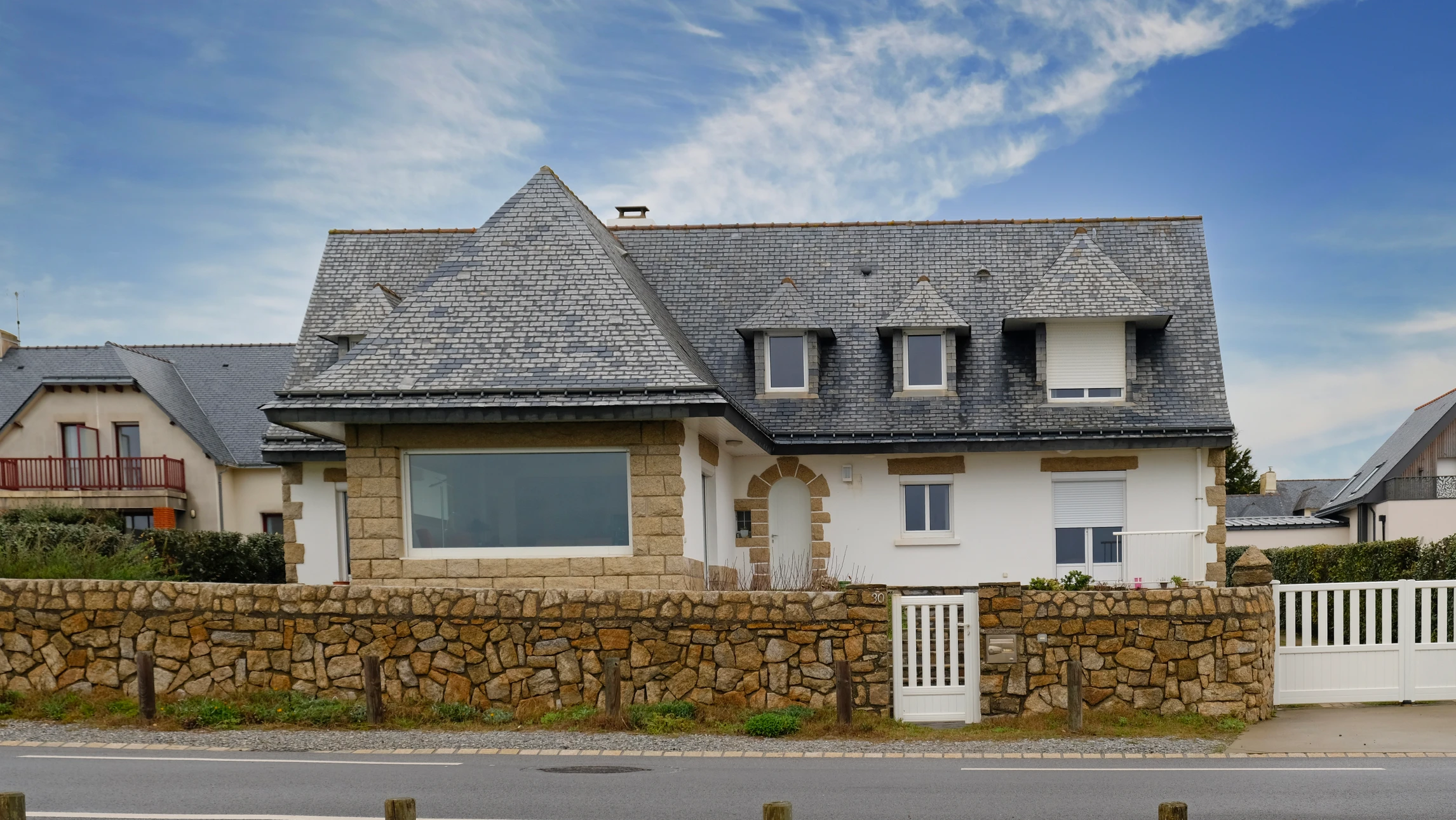 Ouvrier en bâtiment portant casque jaune et chemise à carreaux utilise une scie circulaire électrique pour découper une brique perforée sur chantier de construction
