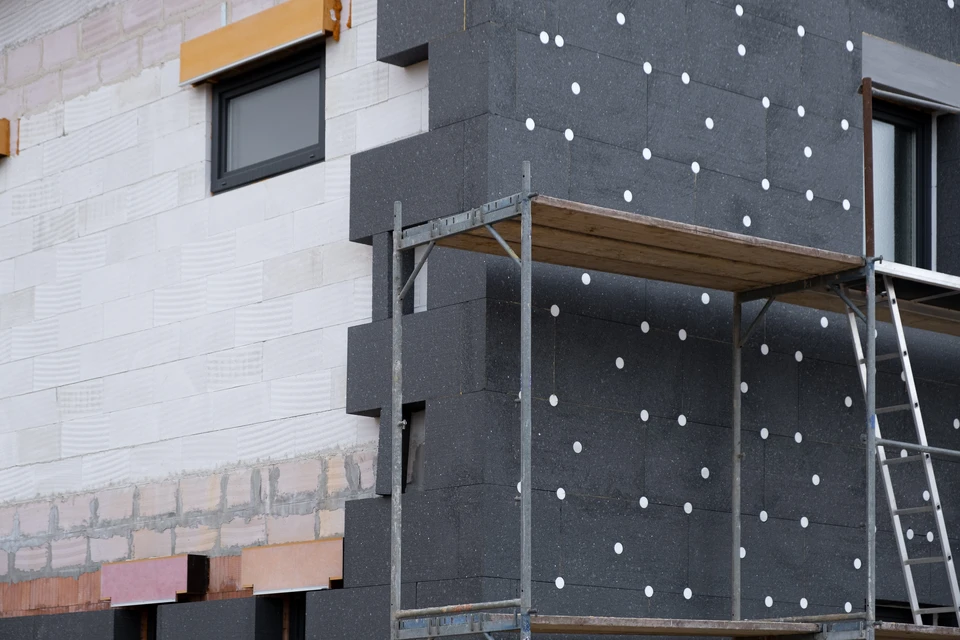 Chantier de construction extérieur avec pose d'isolation thermique par l'extérieur sur façade de maison individuelle